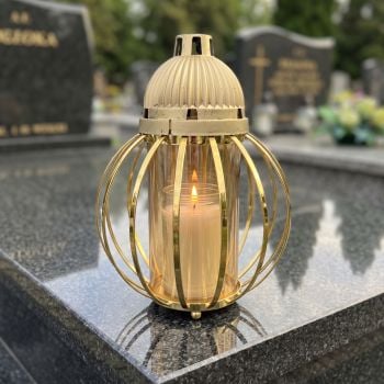 Znicz lampion złoty, kula z drutów na nagrobku w słoneczny dzień