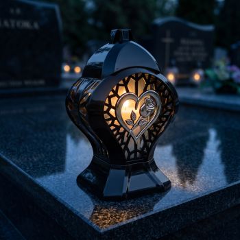 Znicz kapliczka czarno-srebrny z różą w sercu zapalony na nagrobku nocą