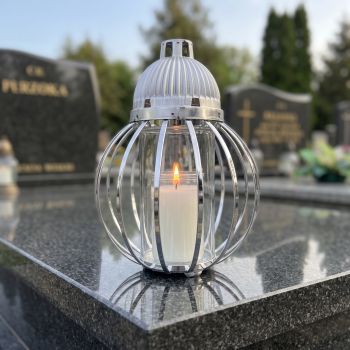 Znicz lampion srebrny, kula z drutów na nagrobku w słoneczny dzień