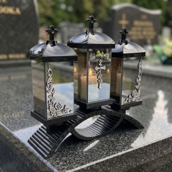 Znicz lampion potrójny czarno-srebrny na nagrobku w słoneczny dzień