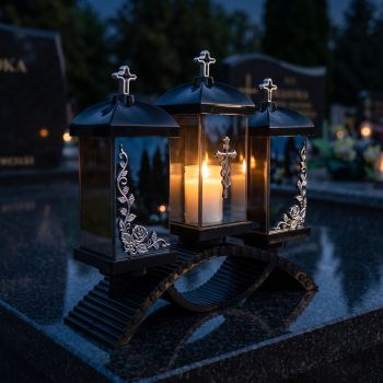 Znicz lampion potrójny czarno-srebrny zapalony na nagrobku nocą