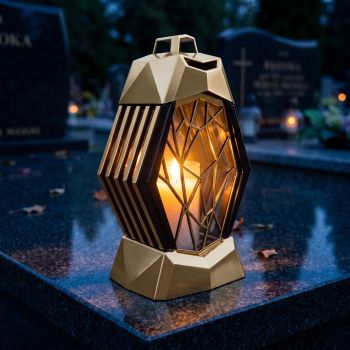 Znicz kapliczka złoty z witrażem zapalony na nagrobku nocą