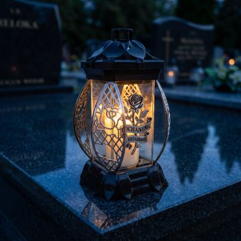 Znicz kapliczka czarno-srebrny „Kochanemu Dziadkowi” zapalony na nagrobku nocą