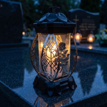 Znicz szklany czarno-srebrny „Kochanej Babci” zapalony na nagrobku nocą