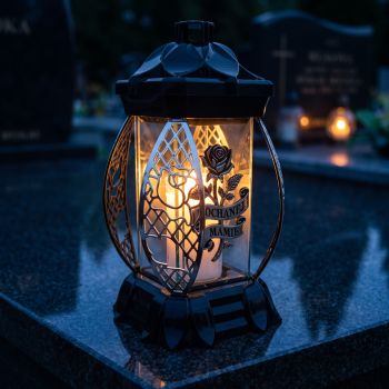 Znicz kapliczka czarno-srebrny „Kochanej Mamie” zapalony na nagrobku nocą